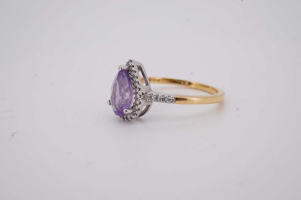 A modern 18ct gold and single stone pear cut amethyst set ring, with diamond chip set border and shoulders, size O, gross weight 3.4 grams. Condition - fair to good